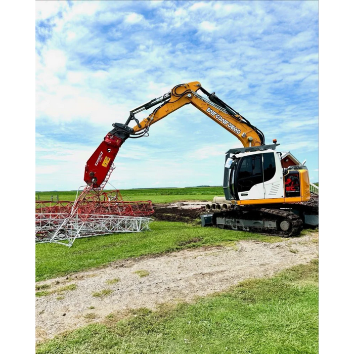 Excavator with demolition shears attachment working on a construction site under a blue sky.