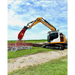 Excavator with demolition shears attachment working on a construction site under a blue sky.