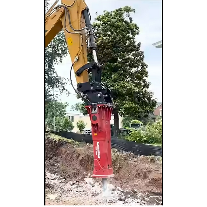 Excavator with a red hydraulic breaker attachment in an outdoor setting.