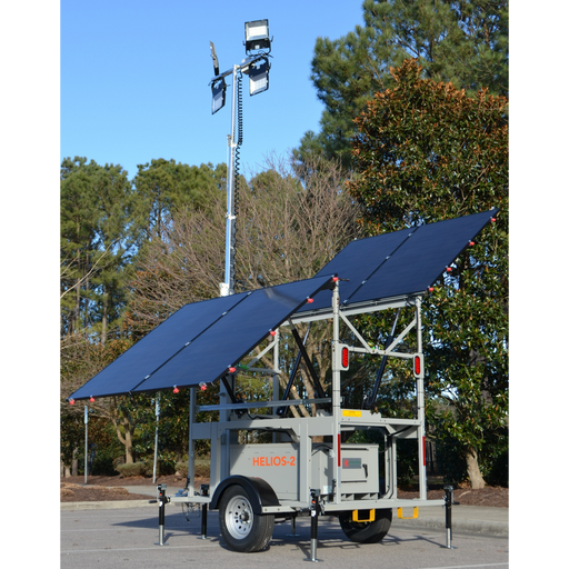 Mobile lighting tower with solar panels on a trailer in an outdoor setting.