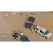 Solar security camera tower with flood lights and solar panels on a trailer hitched to white truck and people in a construction jobsite setting 