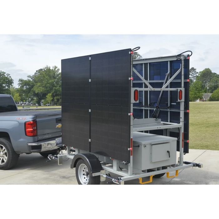 mobile solar security camera trailer being pulled by gray truck