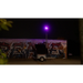 Solar security camera trailer parked in front of a graffiti-covered wall with a red/blue light in the background.