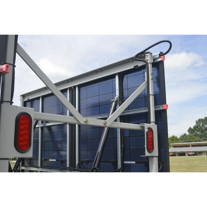 Trailer with a large solar panel on the back, under a clear blue sky.