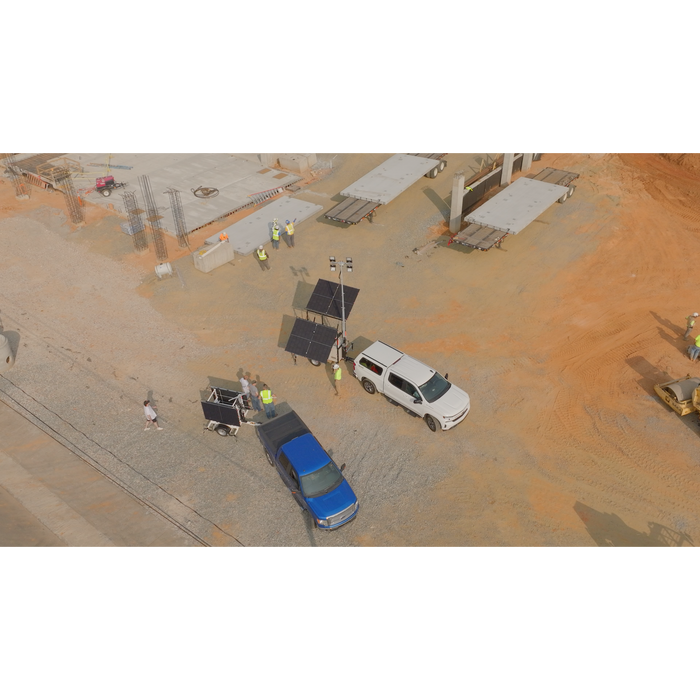 Aerial view of a construction site with mobile solar light tower, vehicles, and workers.