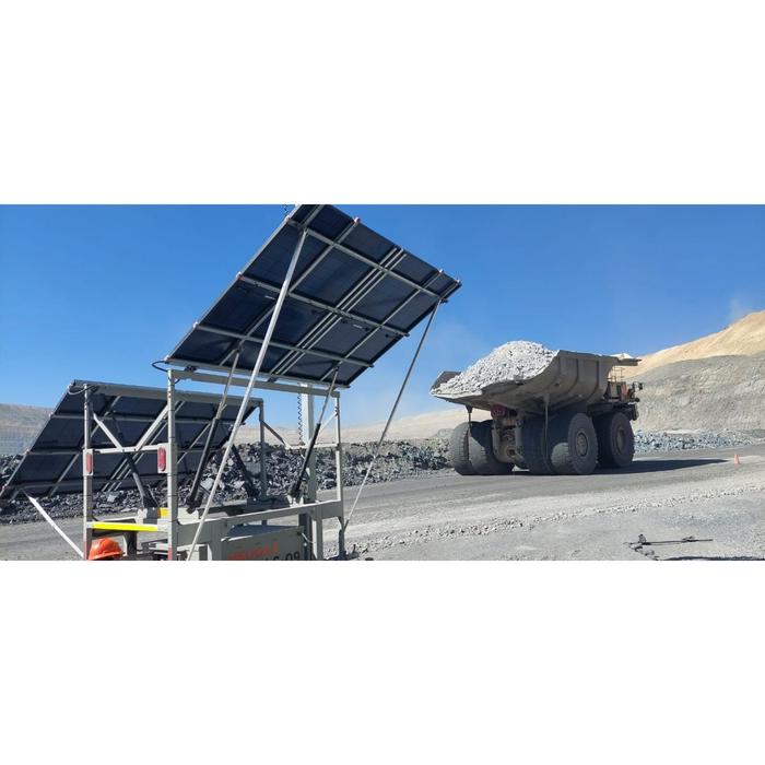 Solar panels on mobile light tower in a mining or industrial setting with a dump truck in the background.