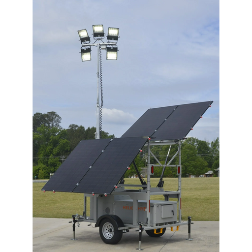 Mobile lighting tower with solar panels on a trailer in an outdoor setting.