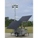 Mobile lighting tower with solar panels on a trailer in an outdoor setting.
