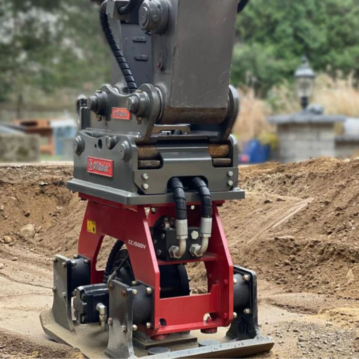 Close-up of a excavator mounted plate compactor by Connect Work Tools for construction tool on a dirt field with blurred background